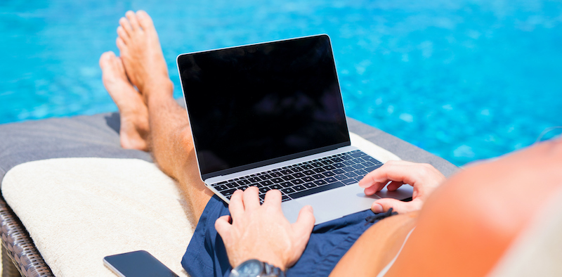 man working on laptop by pool